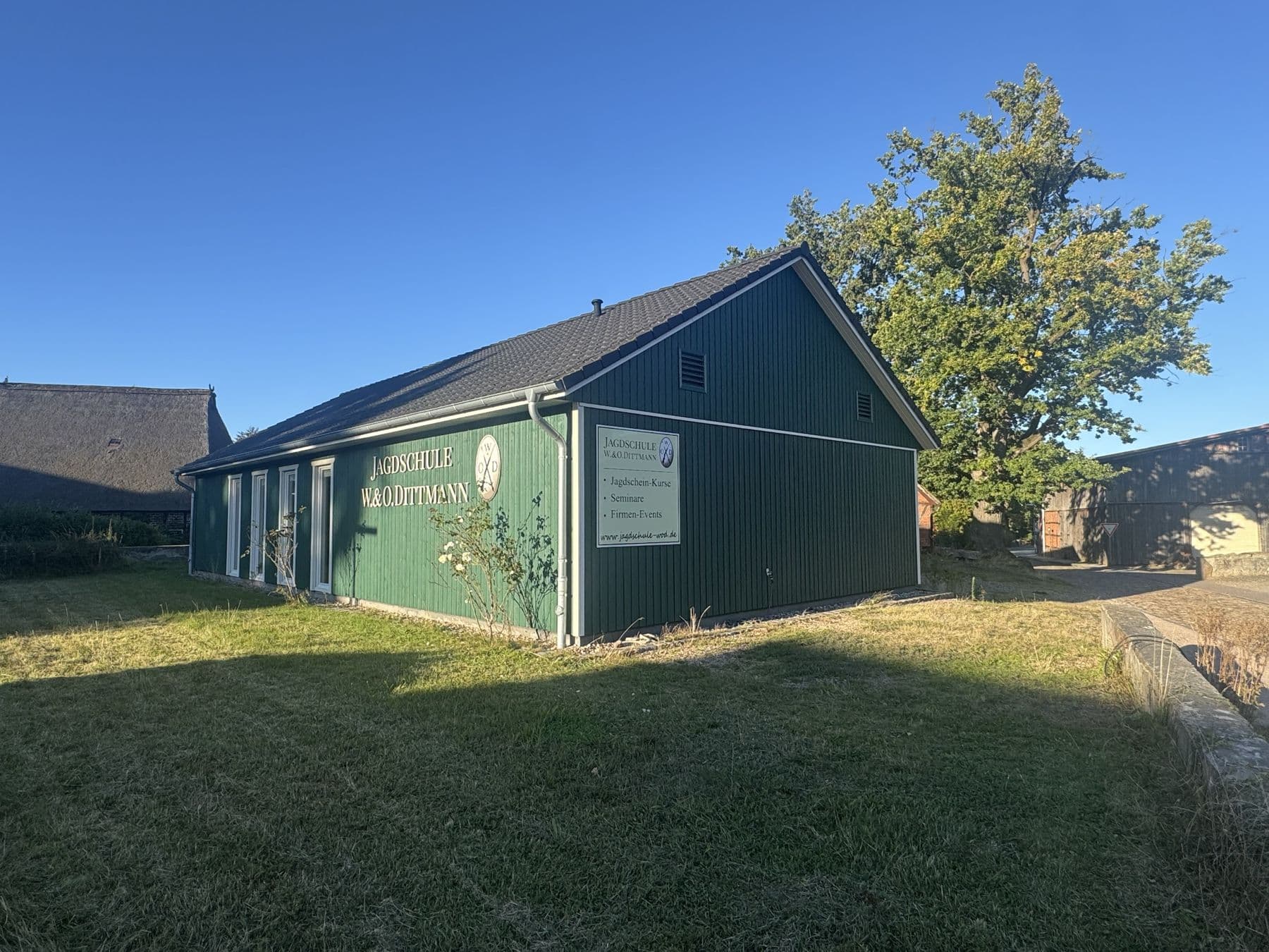 Das grüne Holzgebäude der Jagdschule W.&O. Dittmann im Abendlicht
